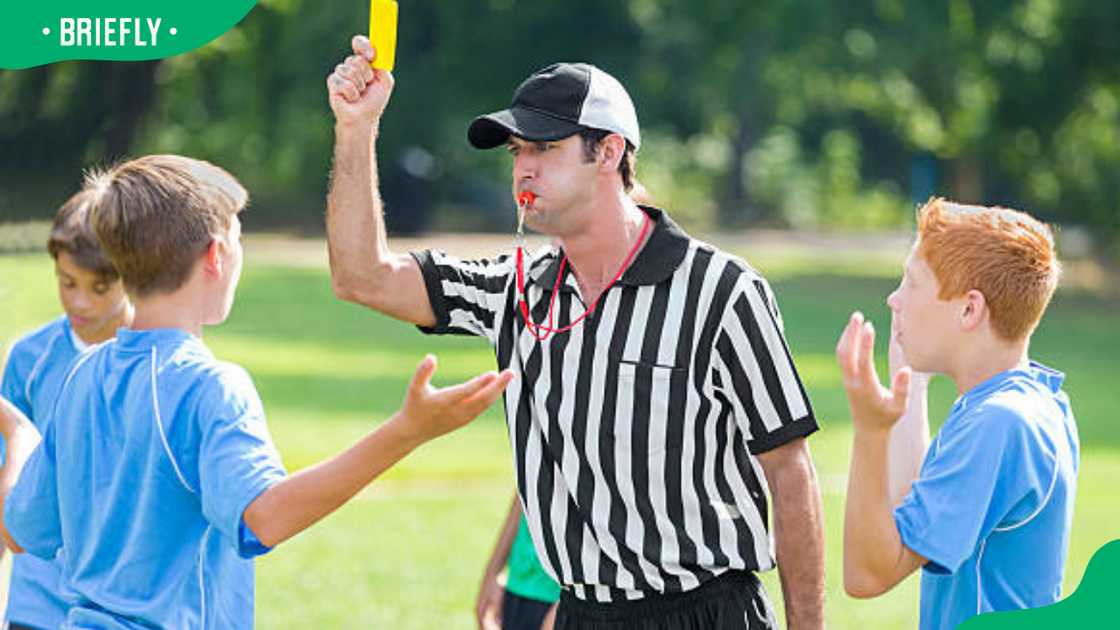 A referee holds up a yellow card during soccer game A referee holds up a yellow card during soccer game