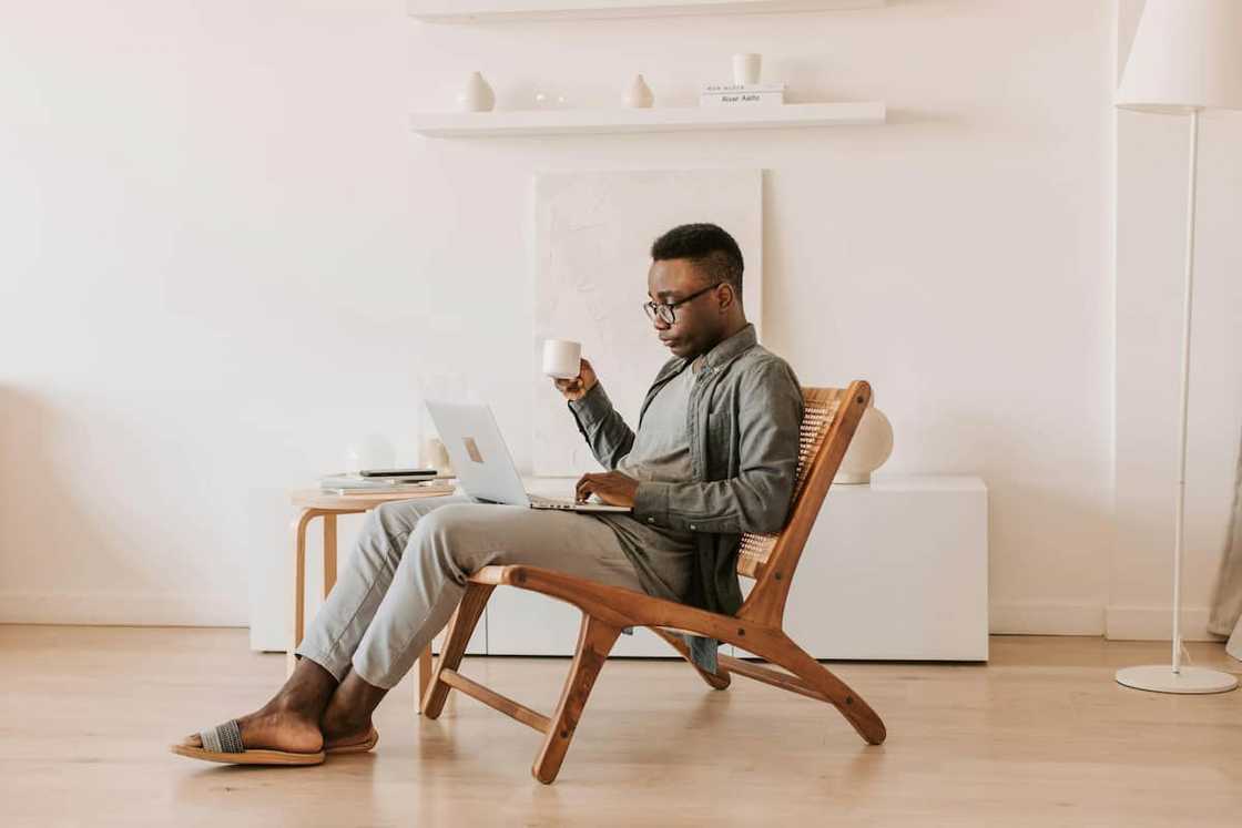 A man in a grey outfit sitting with a laptop on his lap
